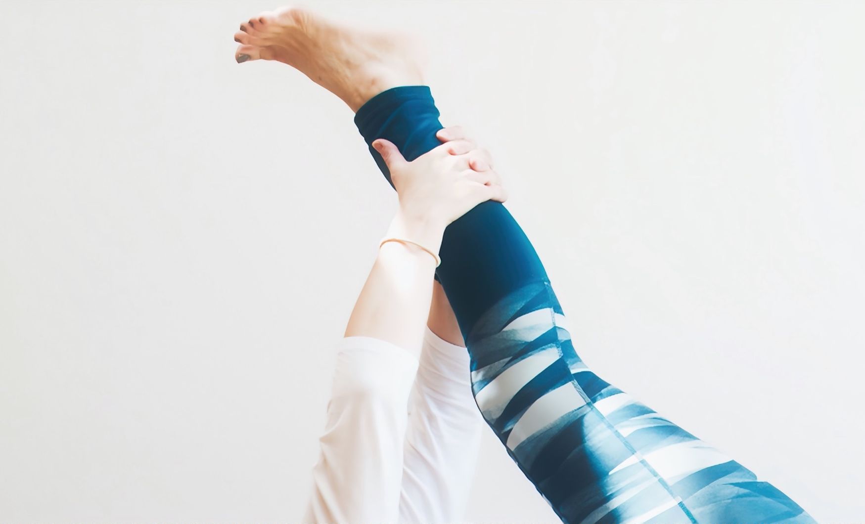 Woman in Pilates pose with leg extended to ceiling.